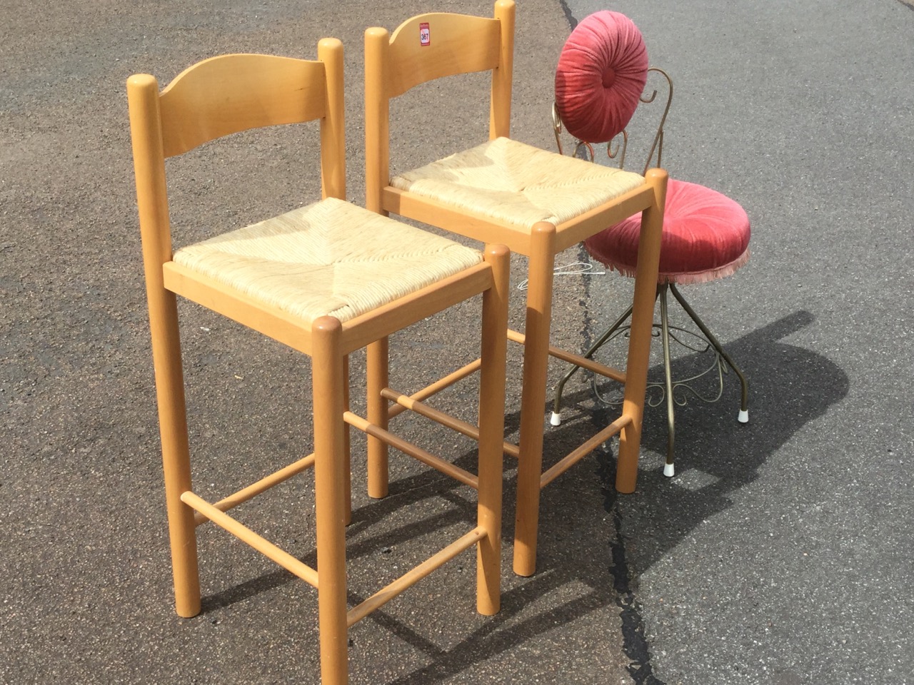 A pair of beech kitchen bar stools with rush seats on column supports; and a kitsch pink upholstered