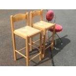A pair of beech kitchen bar stools with rush seats on column supports; and a kitsch pink upholstered