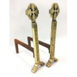 A pair of celtic style brass fire dogs, with circular cross medallions on hammered columns, raised