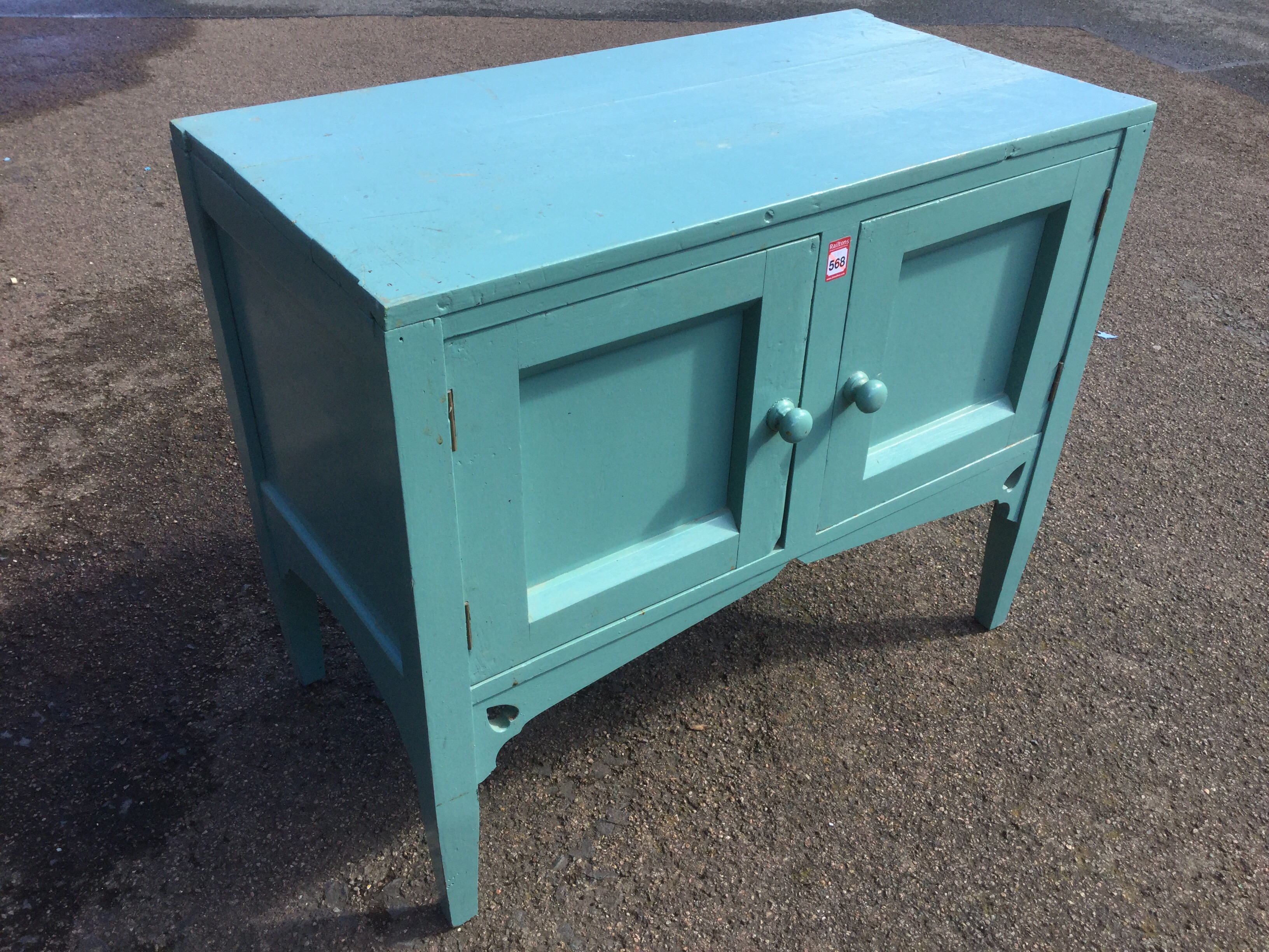 A painted washstand with panelled cupboard doors above aprons pierced with heart motifs, raised on