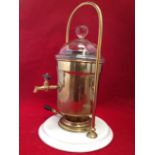 A brass coffee samovar with urn in tubular hooped frame having glass cover with ball handle, the