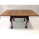 A mahogany draw-leaf dining table, the panelled top raised on acanthus carved cabriole legs with