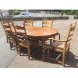 An oak dining table & chair set, the moulded top with spare leaf having rounded ends, raised on