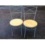 A pair of modern chairs, with circular solid seats raised on tubular metal legs, the backs with