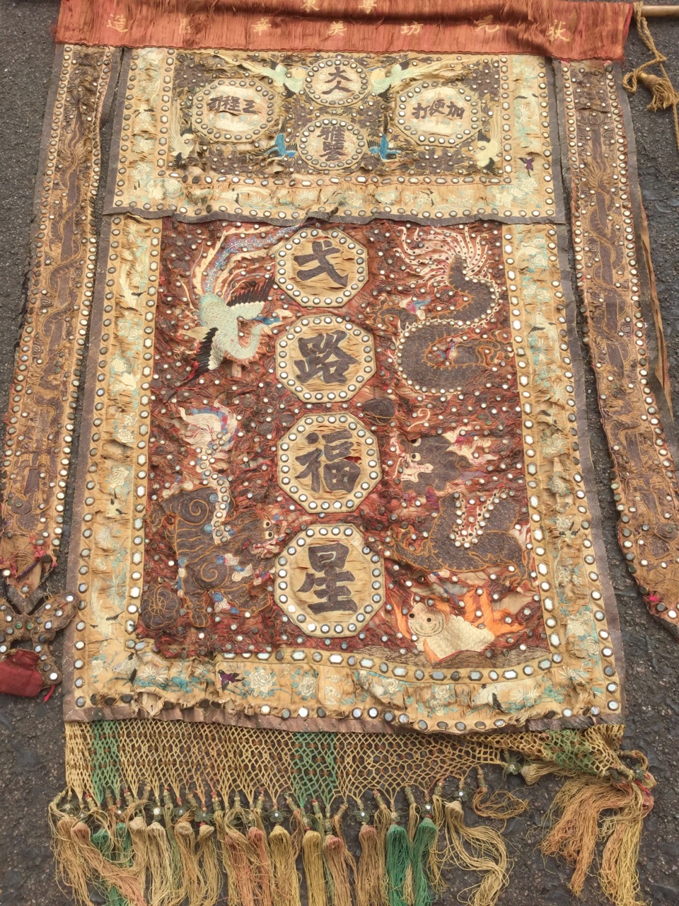 A nineteenth century Chinese banner sewn with embroidered panels and characters in coloured & gilt