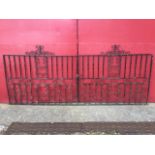 A pair of wrought iron driveway gates, each with twisted bars around central scrolled panel, the