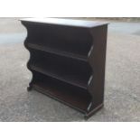 An oak open bookcase, the moulded shelves with shaped aprons, with waved sides.