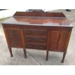 An Adams style mahogany sideboard, with foliate scroll carved upstand above a moulded top, having