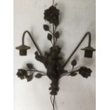 A hanging wrought iron wall light, with blindfolded cherub framed by floral branches beneath two