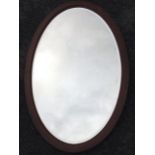 A large oval mahogany framed mirror with bevelled plate.