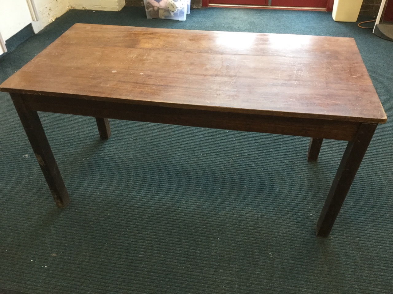 A solid rectangular hardwood dining table, the top on square column legs.