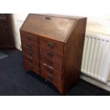 A stained bureau with fallfront enclosing a fitted interior with two small drawers, above a chest of