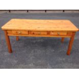 A pine kitchen table with rectangular canted top above three frieze drawers mounted with brass