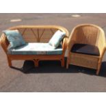 A cane sofa with rounded plaited back rail and arms above a diamond shaped caned back panel, with
