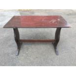 A rectangular oak table with vase shaped trestle style supports on sledge feet, joined by