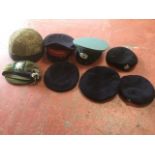 Eight military hats, berets and a helmet, mounted with various regimental badges. (8)