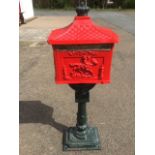 A metal postbox, the container with letterbox embossed with postboy & horn panels beneath a