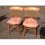 A pair of beech spindleback kitchen chairs, with solid seats raised on turned legs and stretchers,