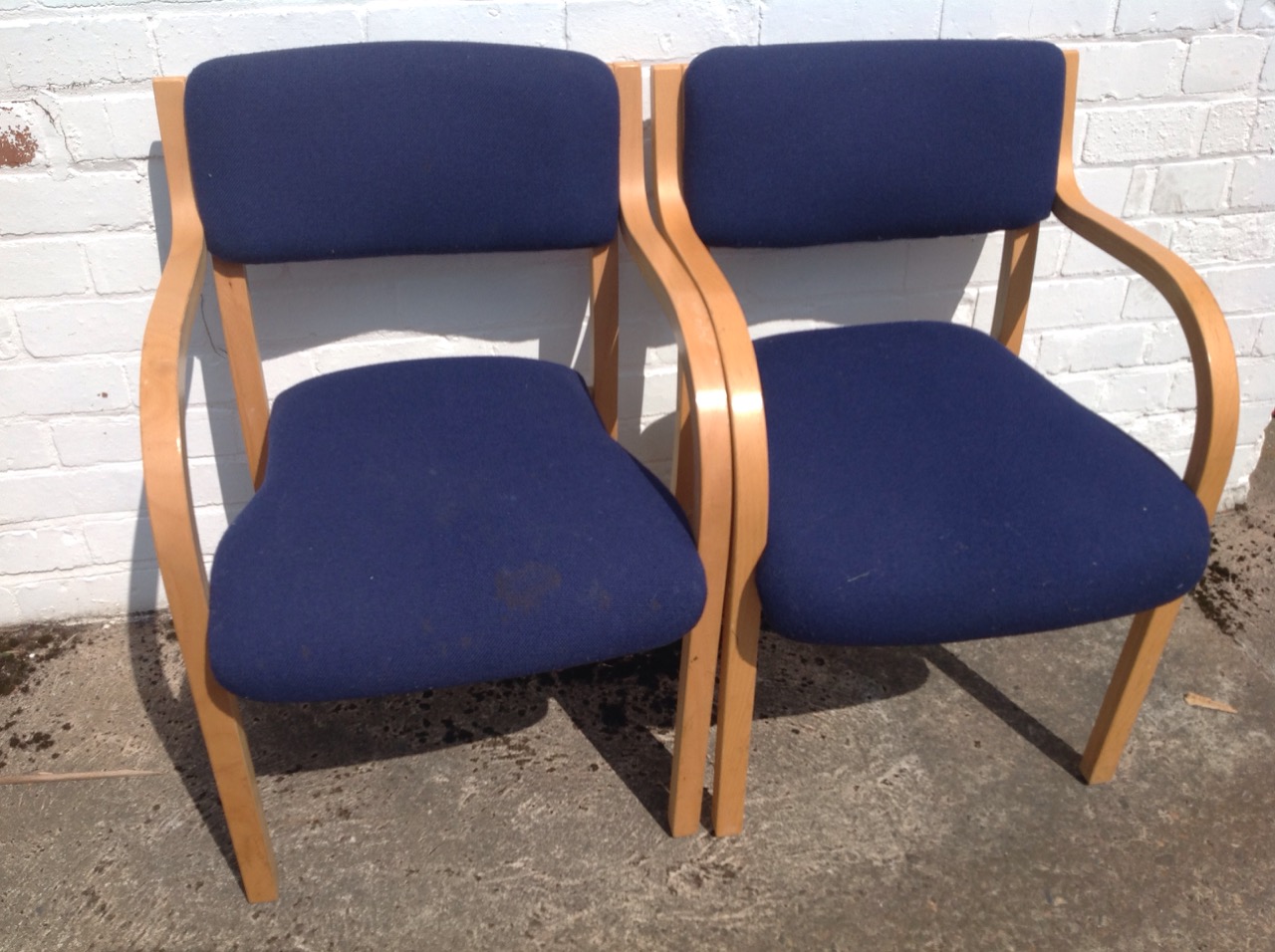 A pair of contemporary beech armchairs, with padded upholstered backs and downswept arms framing