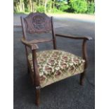 A late Victorian carved armchair, the back with floral medallion framed by leaf scrolls, the