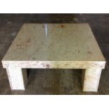 A large polished granite coffee table, the square slab top supported on four channelled column legs.