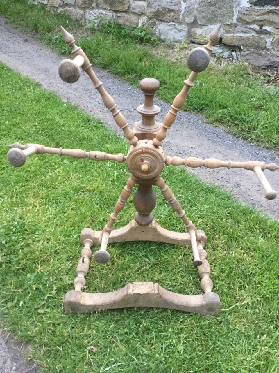 An antique woolwinder, the wheel with spindles around a hub, on turned column with shaped stand -