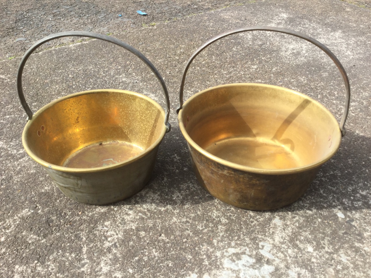 A graduated pair of Victorian brass jam pans with rolled rims and riveted iron handles. (2)