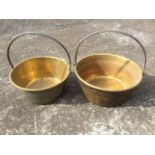 A graduated pair of Victorian brass jam pans with rolled rims and riveted iron handles. (2)