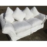 A Delcor sofa with padded back and arms having down loose cushions, currently fitted with white