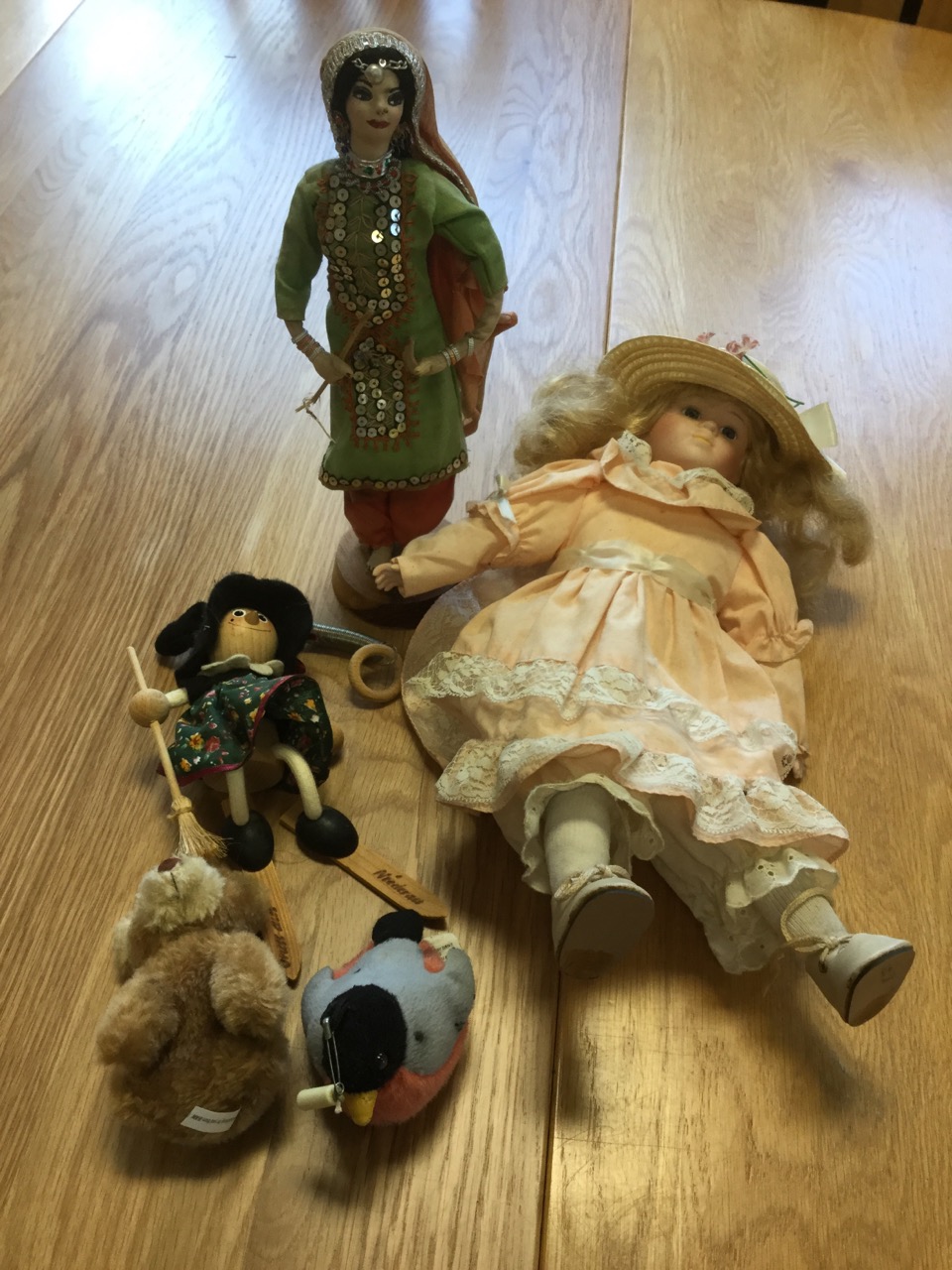 A porcelain headed girl doll in pink dress & straw hat; an Austrian wood skiing novelty doll; two