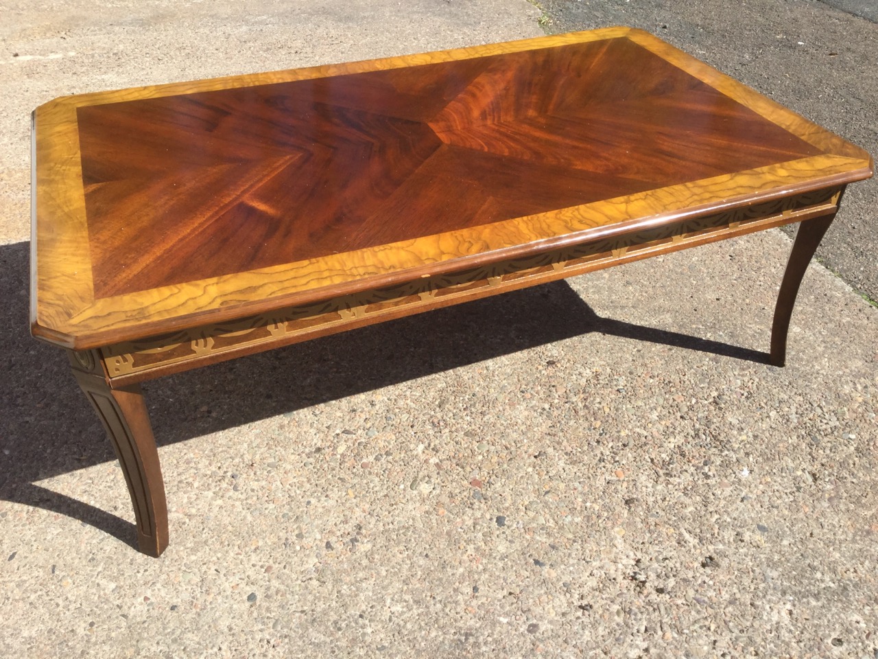 A walnut coffee table, the quarter veneered crossbanded top with canted corners above a frieze