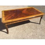 A walnut coffee table, the quarter veneered crossbanded top with canted corners above a frieze