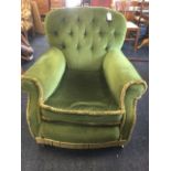 An Edwardian upholstered armchair, with button back and padded arms above a loose cushion and sprung
