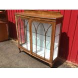 An oak bowfronted display cabinet with shaped upstand to moulded top above gothic astragal glazed