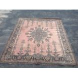 A Wilton style carpet woven in the oriental style with blue floral medallion on pink field