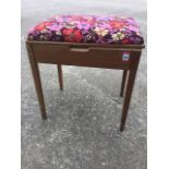 A 60s walnut piano stool with upholstered lifting lid, raised on square tapering column legs.