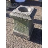 A composition stone urn of square moulded shape raised on plinth.