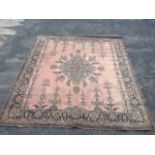 A Wilton style carpet woven in the oriental style with blue floral medallion on pink field framed