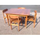 A 1970s teak dining room table & chair set, the draw-leaf table having rounded top, and the four