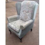 A wing armchair with button upholstered back