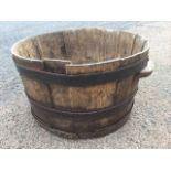 An old oak planter of barrel form having shaped handles and hooped metal bands enclosing the staves.