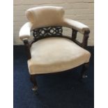 An upholstered captains chair with carved pierced fretwork splats beneath rounded arms,