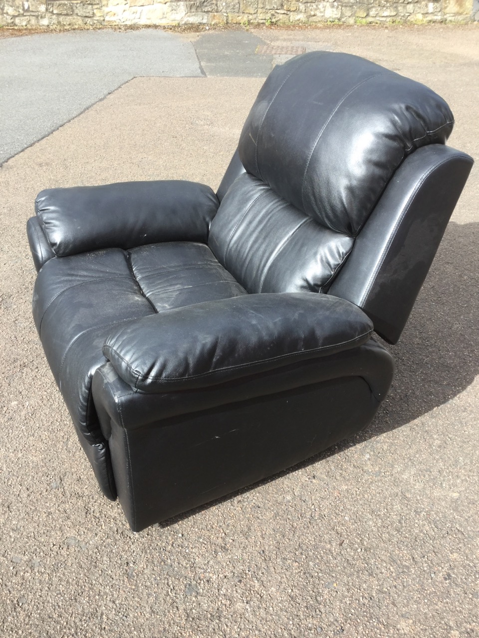 A contemporary leather reclining armchair, with padded back, arms and seat, complete with integral