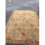 A Wilton style carpet woven with hexagonal medallions on busy floral fawn field, bordered by flower