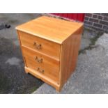 A small modern pine chest of three drawers mounted with brass handles above a shaped apron.