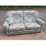 A button upholstered contemporary sofa in tapestry style material having loose cushions