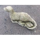 A composition stone otter, modelled lying on rocks