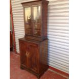 A stained oak cabinet with moulded cornice above glazed doors enclosing shelves,