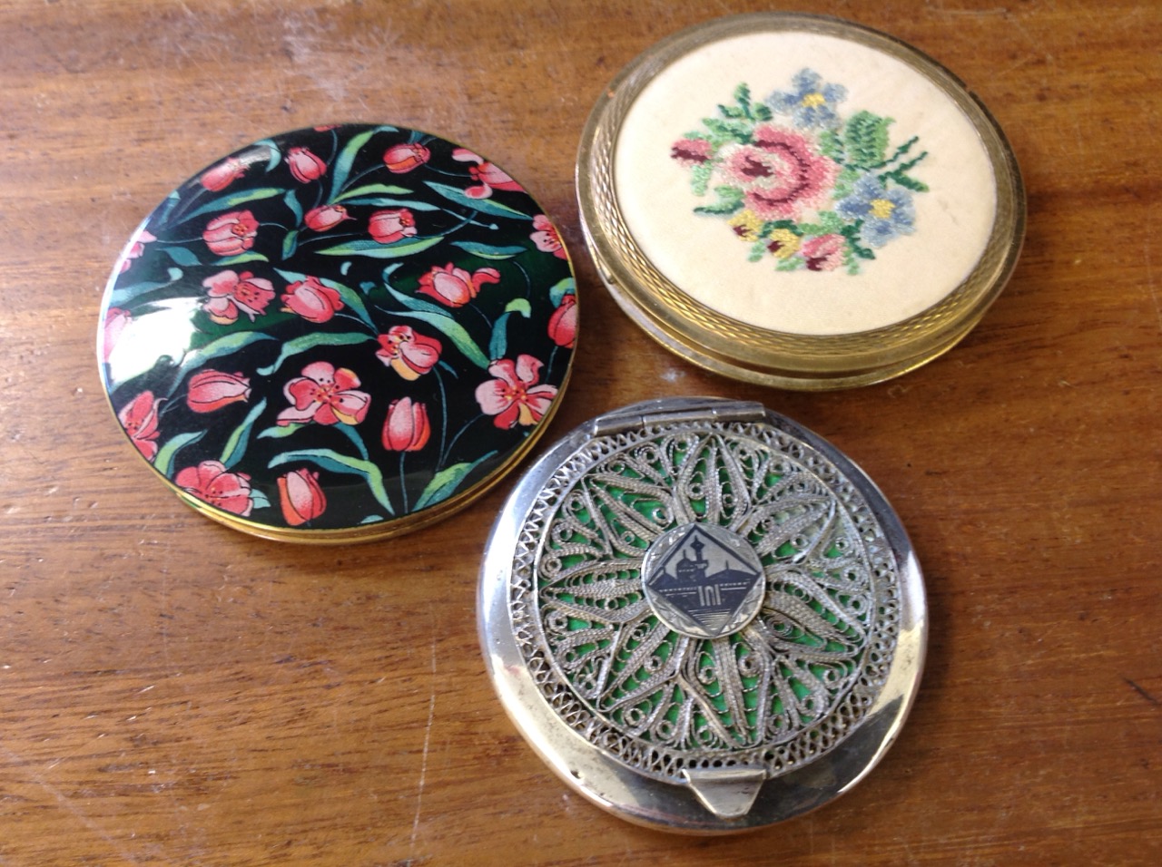 An Egyptian neilo inlaid silver metal compact with filligree lid; a cased Stratton floral enamelled