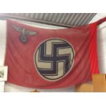 A massive German flag printed with central circular black & white swastika on red ground
